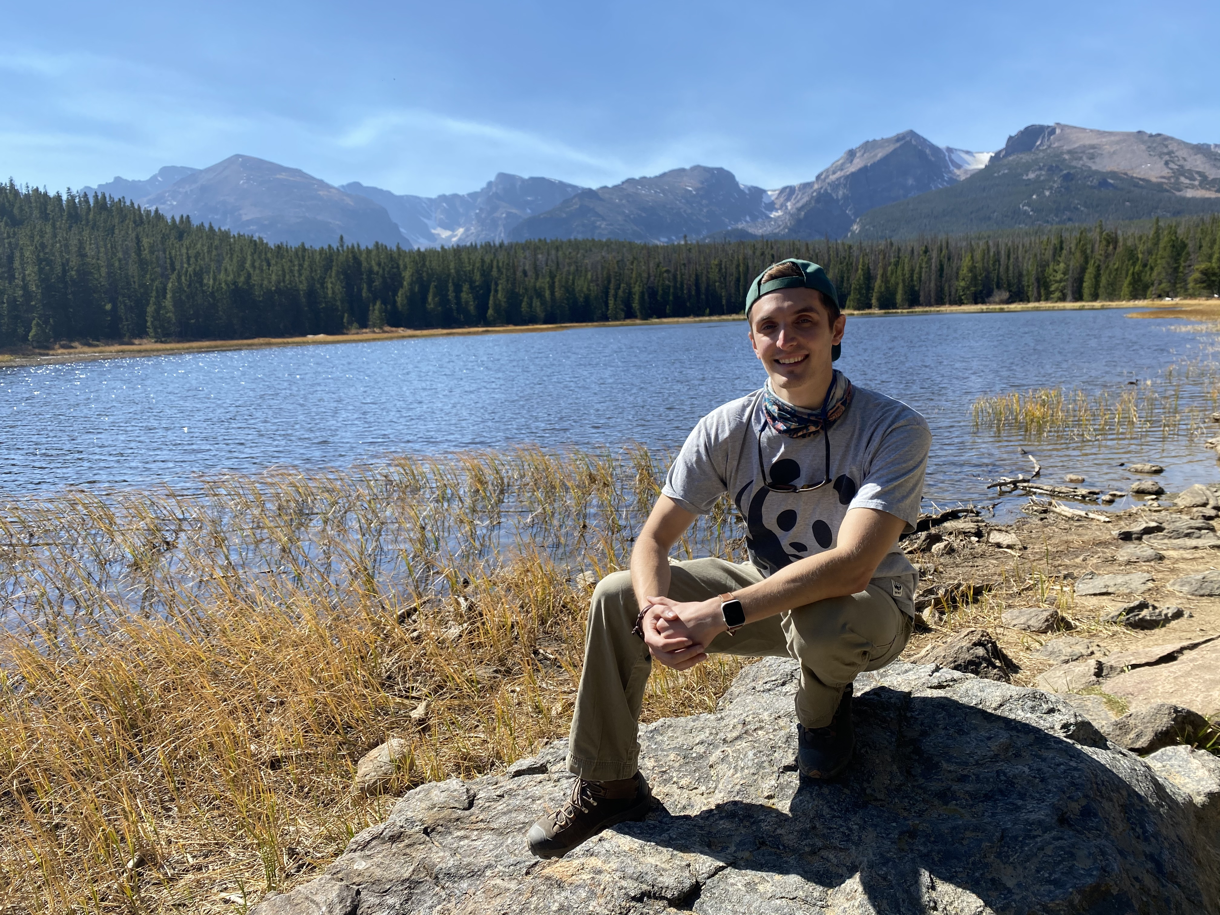 Zachary Dvornicky-Raymond shown sitting by a lake with mountains in the background