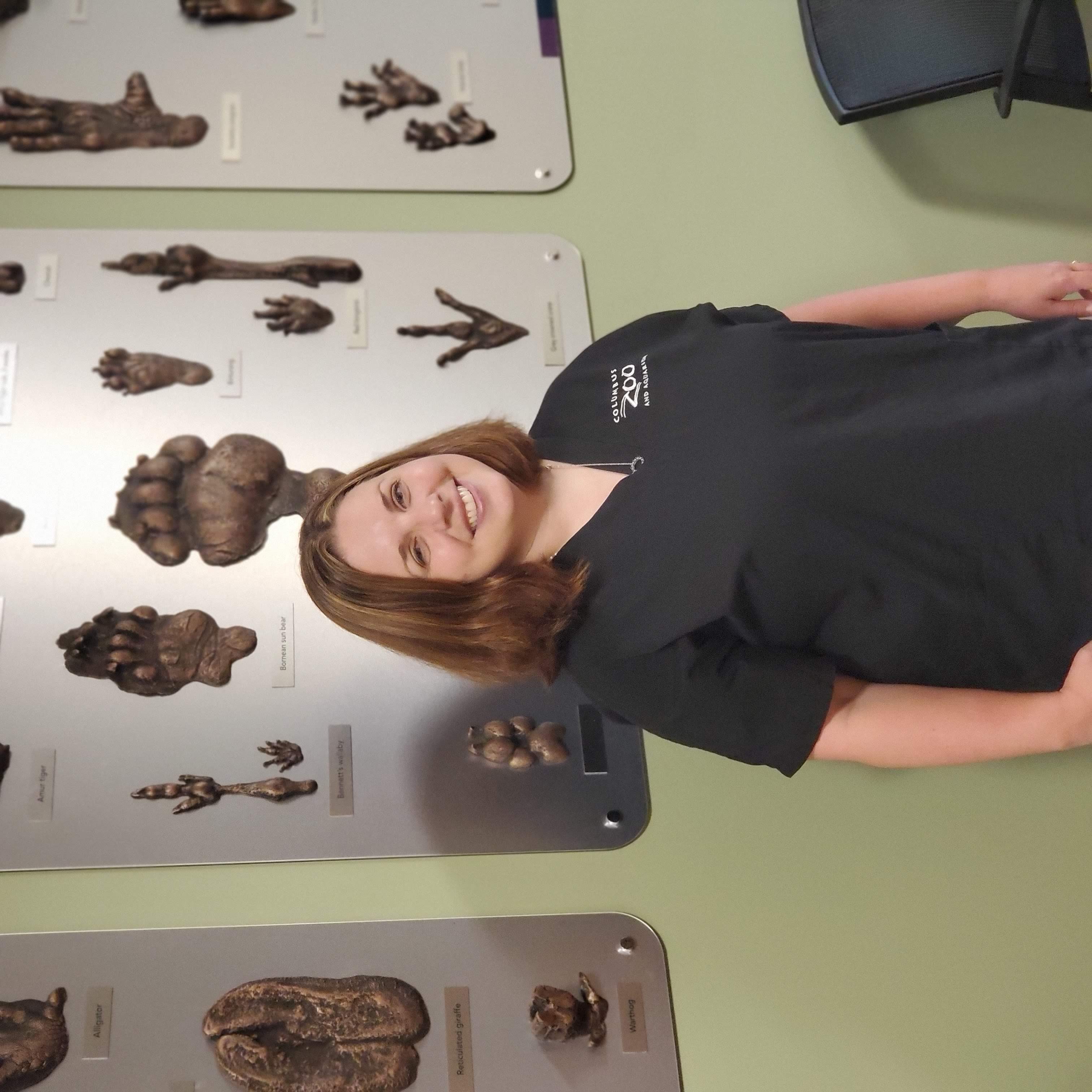 Dr. Katie Seeley standing in front of an infographic and smiling at the camera.