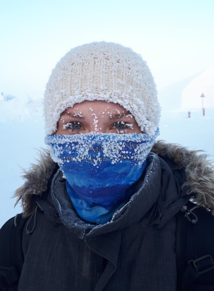 Kayla is looking at the camera, her face is covered in snow.