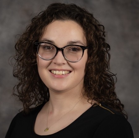 Brenna Lashbrook wearing a black shirt and glasses, smiling at the camera.