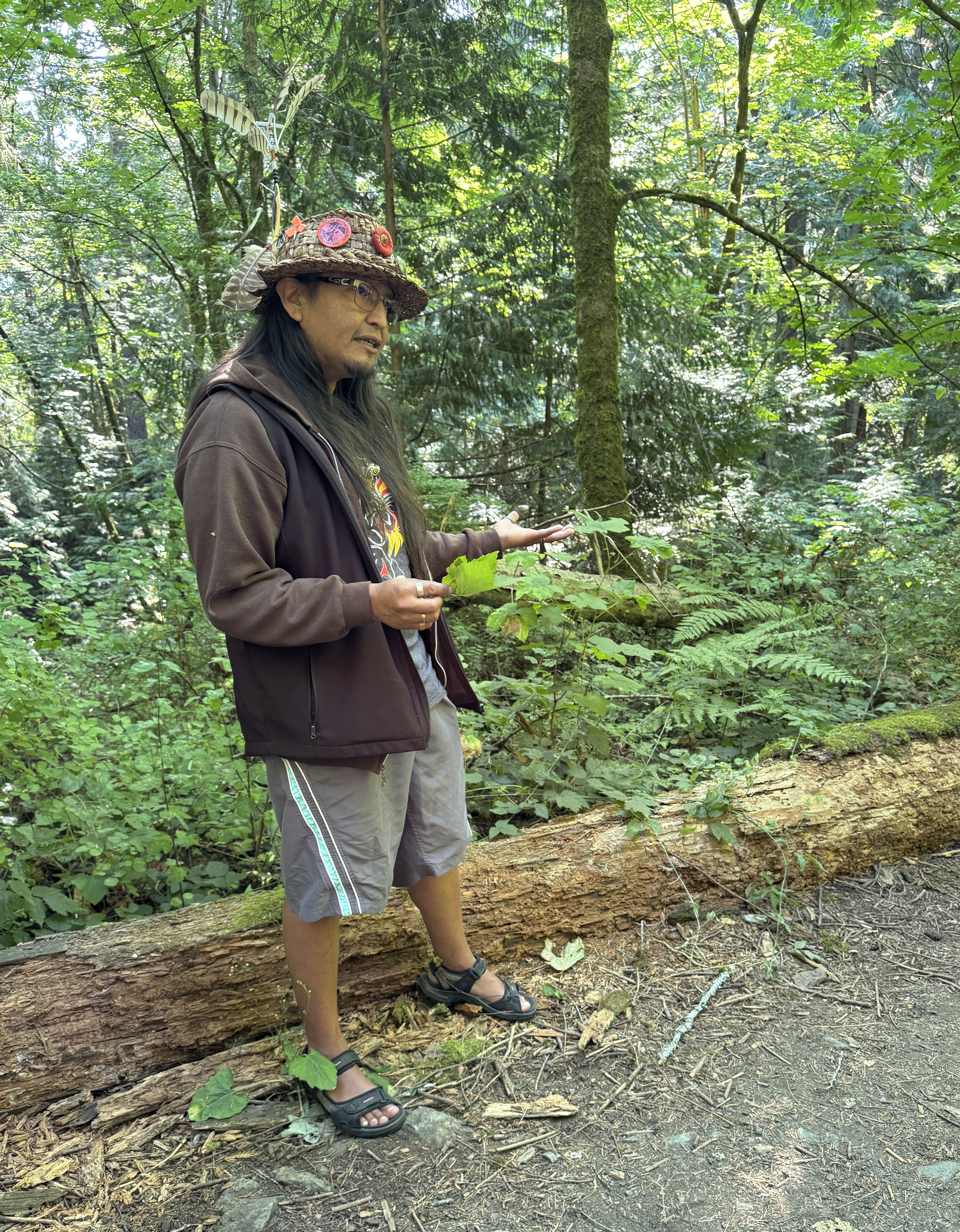 A man wearing a hat standing in the woods.