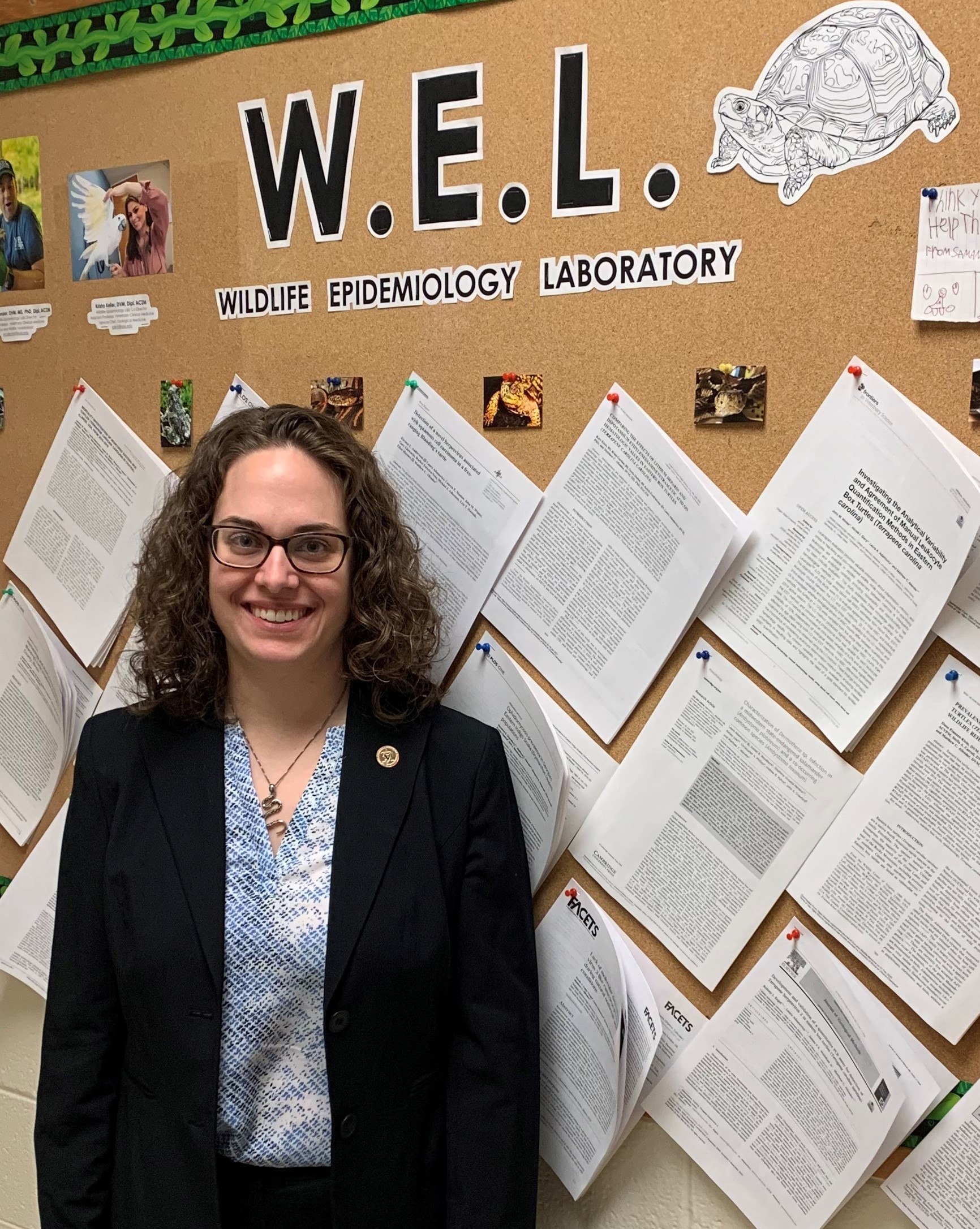 Dr. Haynes is standing in front of a bulletin board with several papers tacked up.