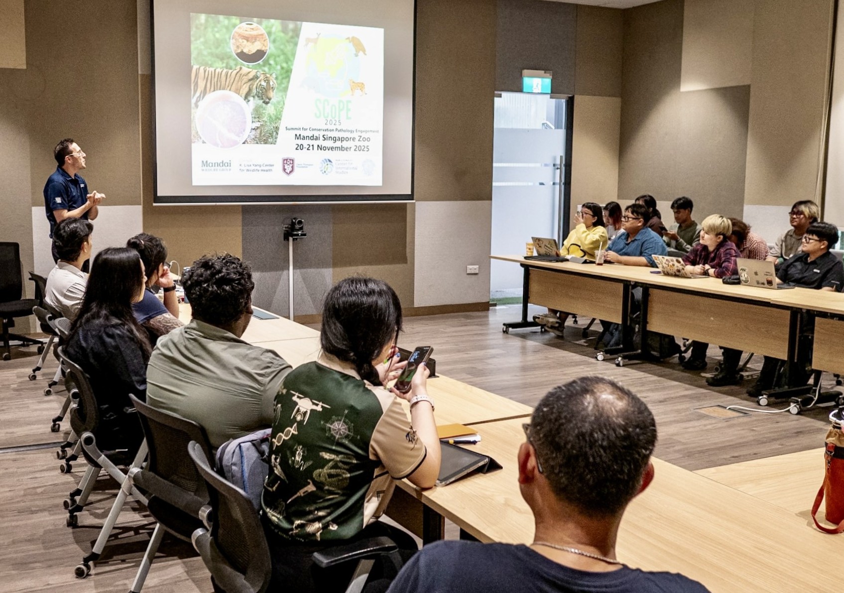 Dr. Carmen Smith stands next to a projector screen showing a slide while a group of people look on.