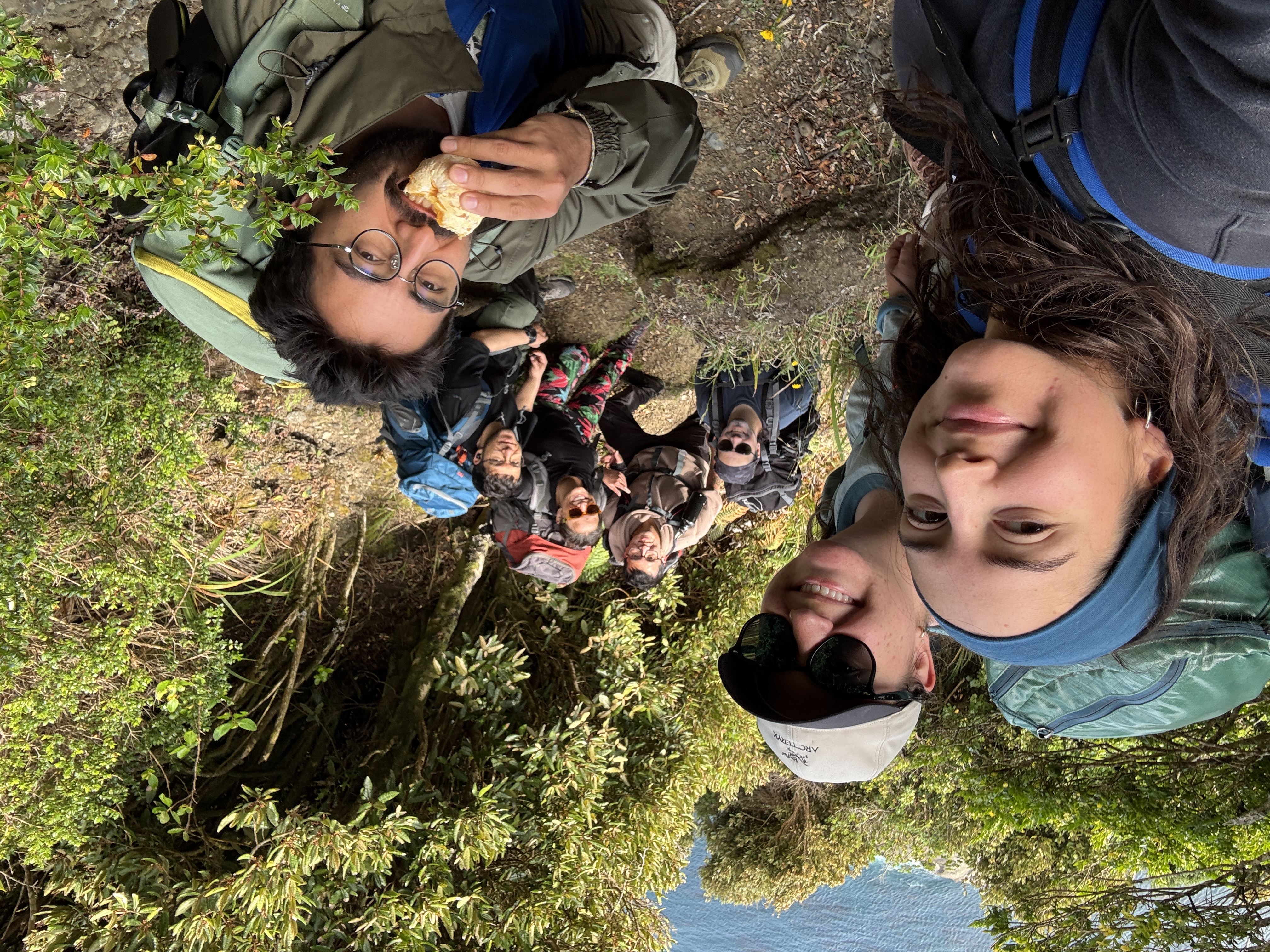 A group of people smiling at the camera with a mountain in the background.
