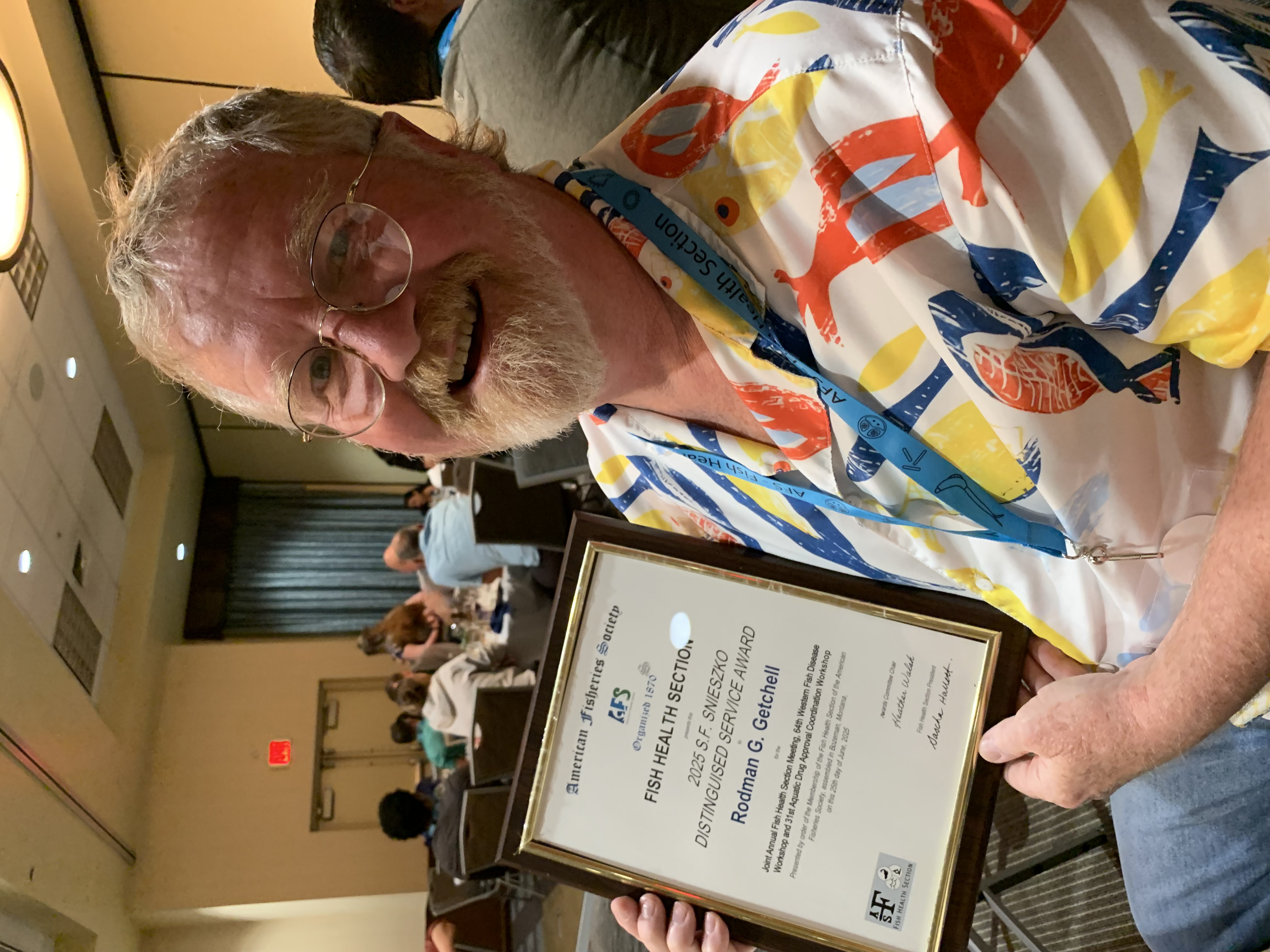 Rod is holding an award and smiling at the camera.