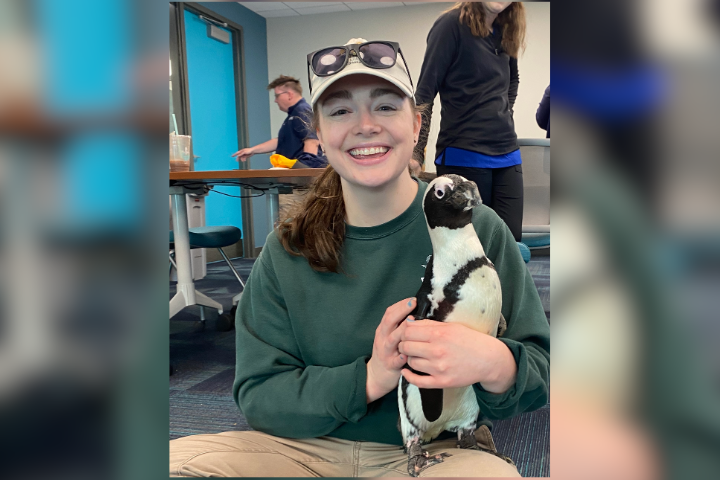 Kathleen holding a penguin and smiling at the camera.