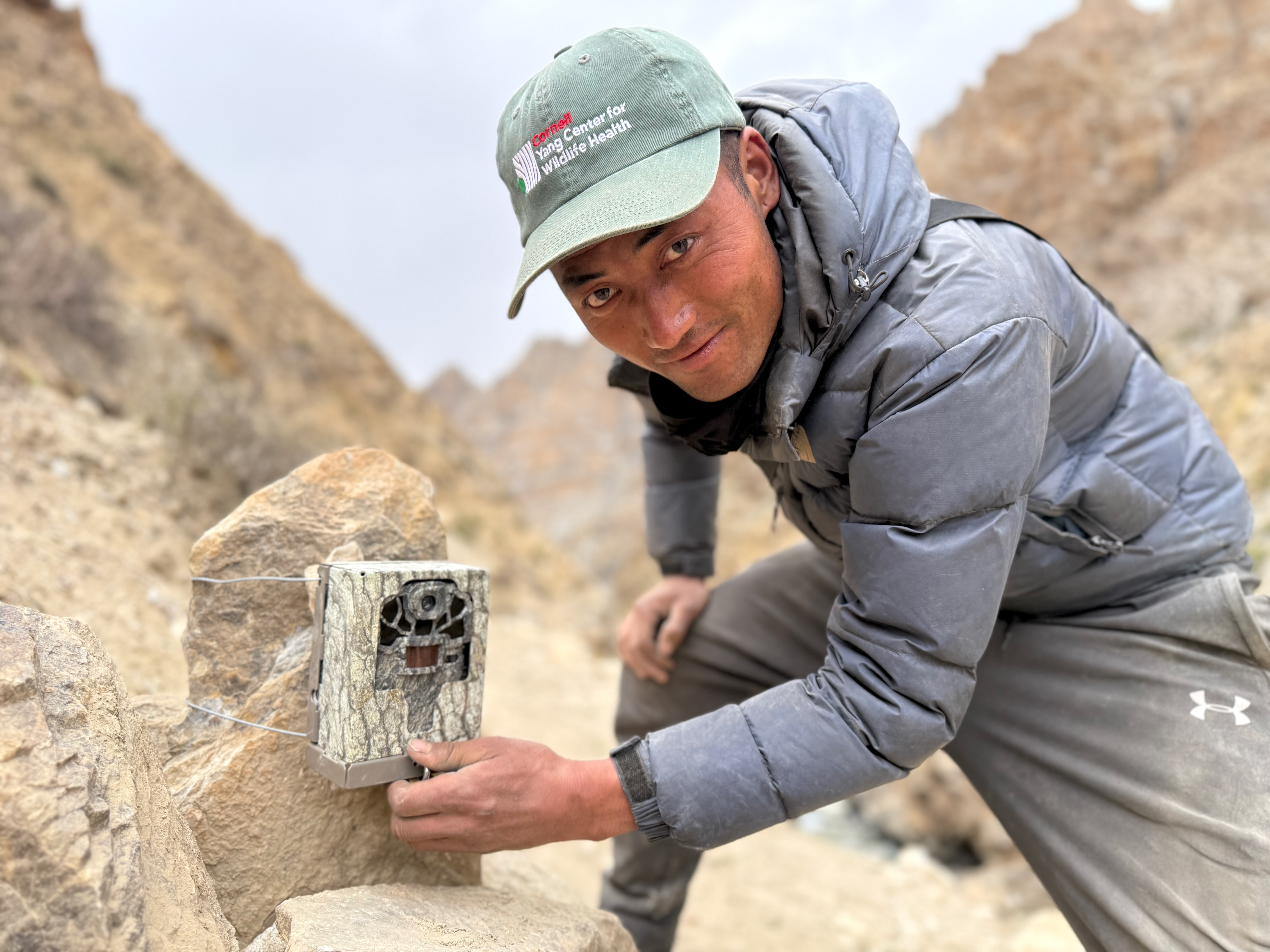 Person wear CYCWH hat sets up camera in the mountains