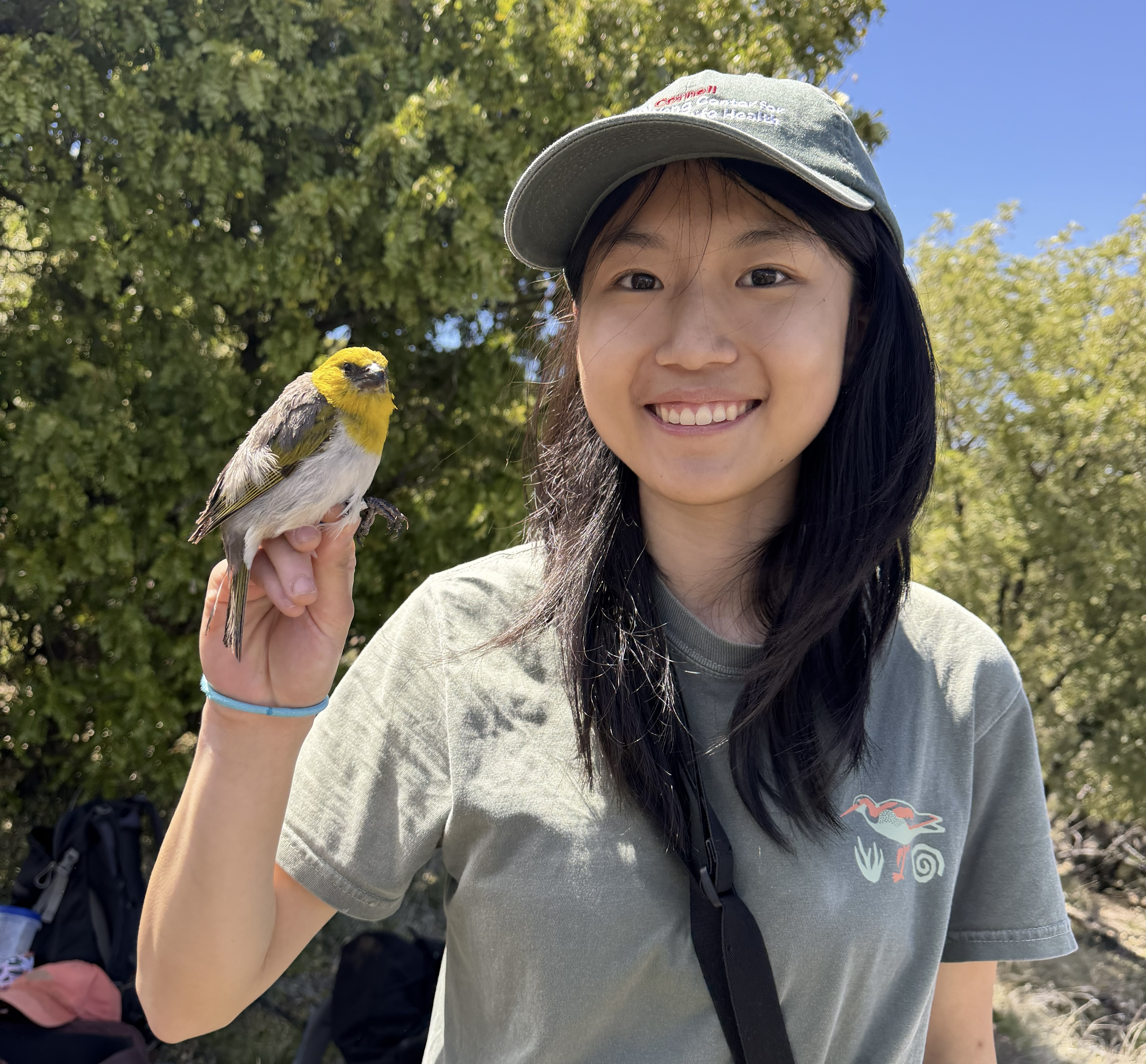 Allison smiling at the camera while a yellow bird is perched on her hand.