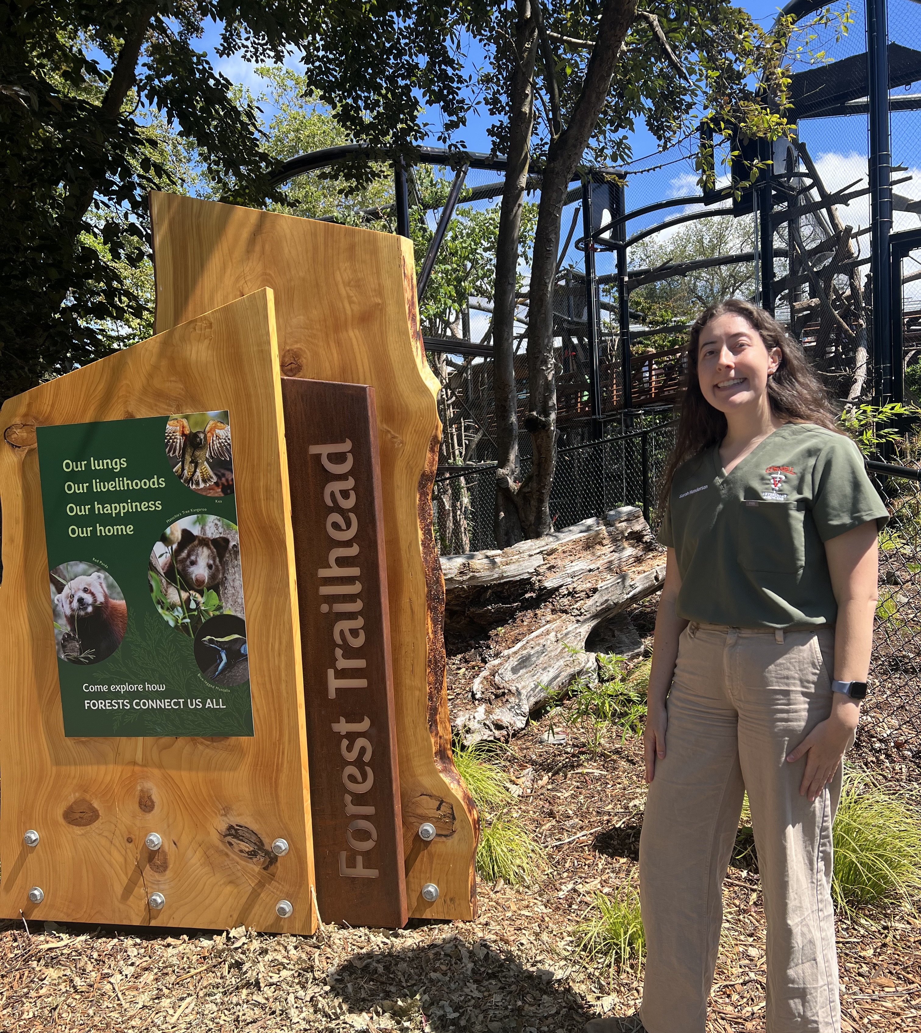 Sarah stands in front of the forest trailhead