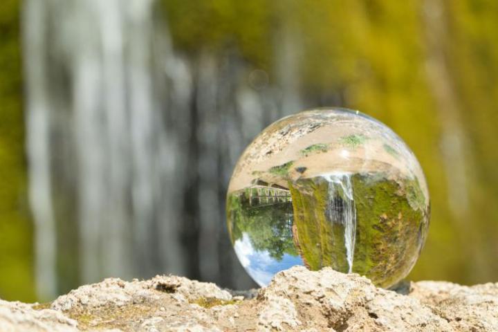 An image of a waterfall reflected in a globe made of glass.