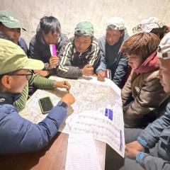 A group seated around a map with people pointing at the map