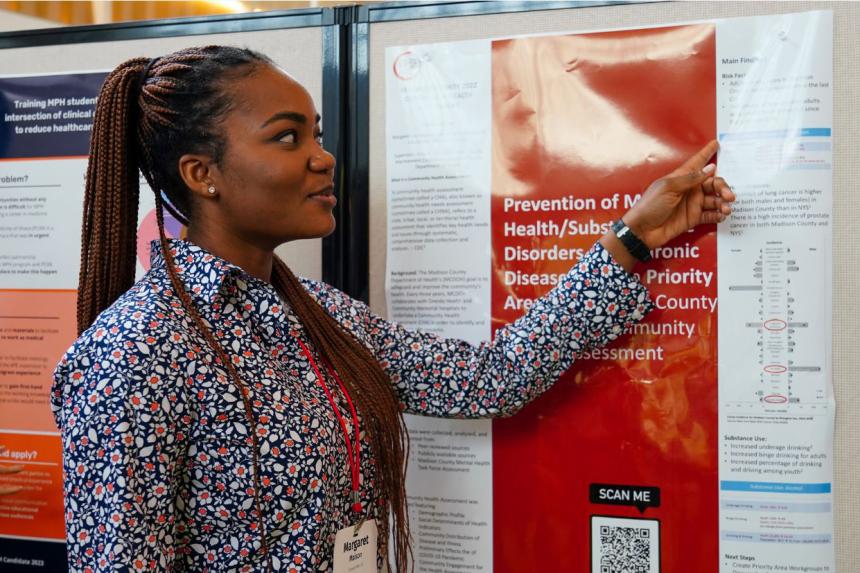 A student at the symposium poster session showcasing and discussing her work.