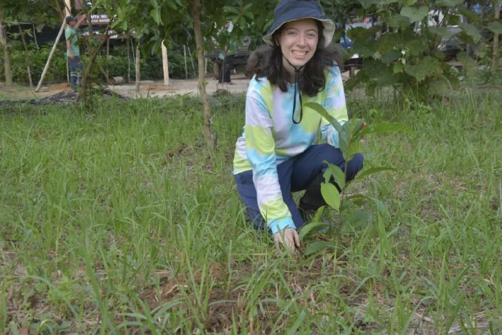 Adora is kneeling in the green grass and smiling at the camera.