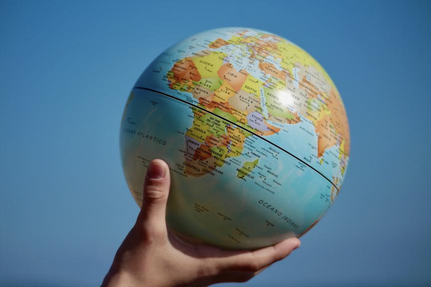 A hand holding a globe