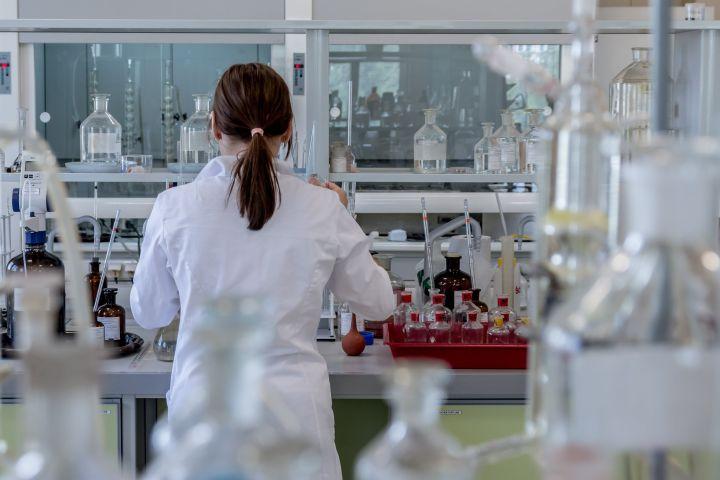 Person standing in a white lab coat working in a lab.